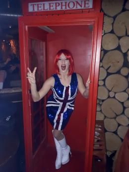 The Cosmic Girls 90s tribute act in telephone box wearing a union jack dress